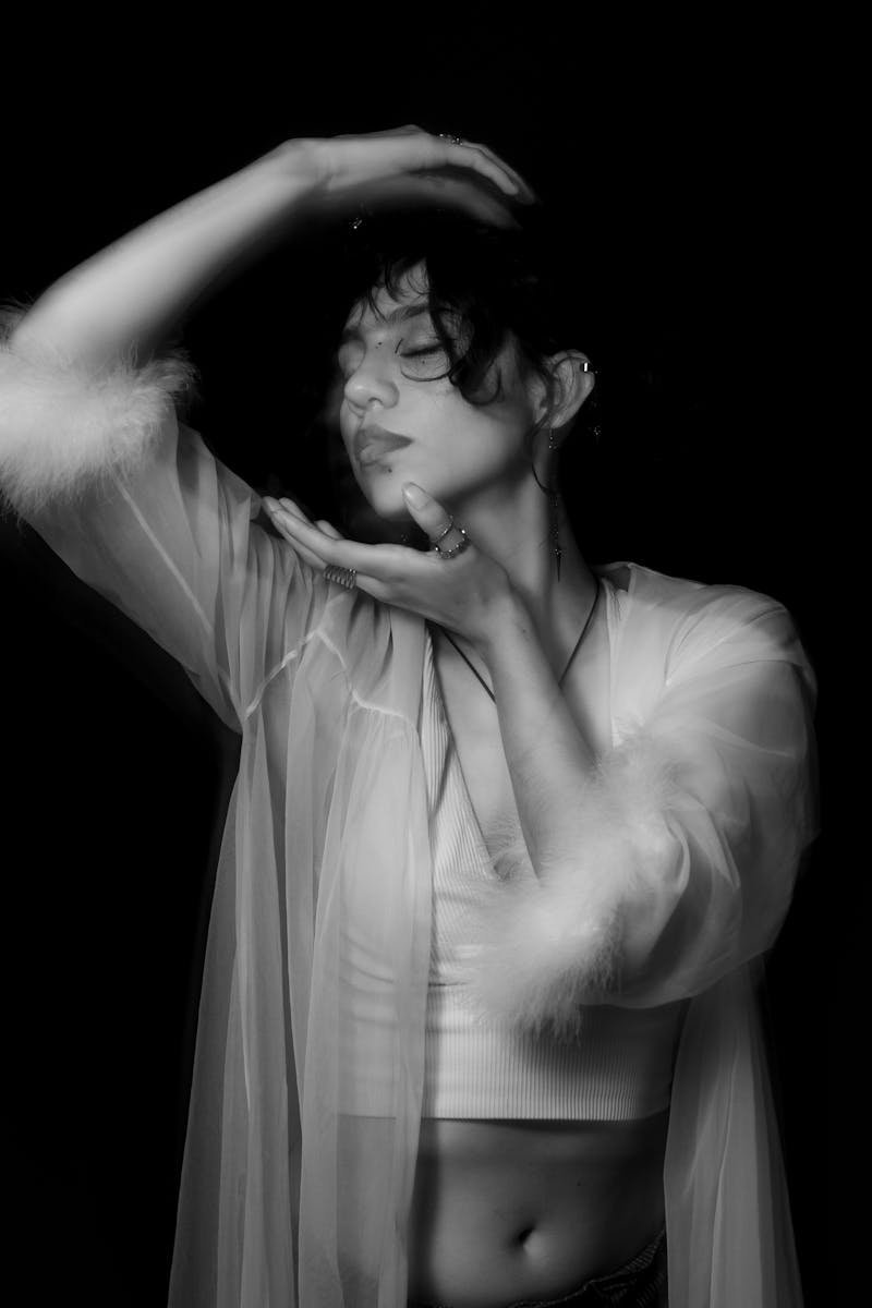 Artistic black and white portrait of a woman in a sheer robe, capturing elegance and emotion.